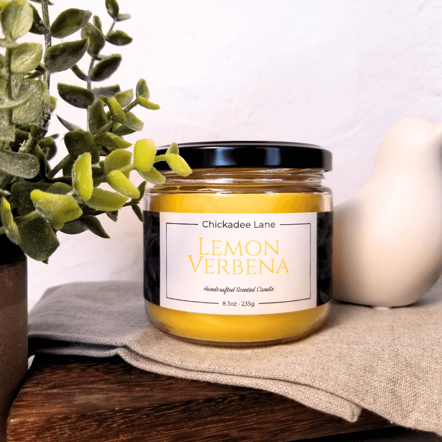 Lemon Verbena candle sitting on a shelf between a plant and a porcelain bird.